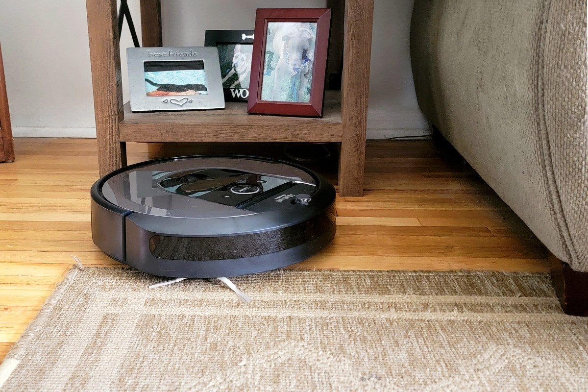 iRobot Roomba i8+ next to furniture on wood floor