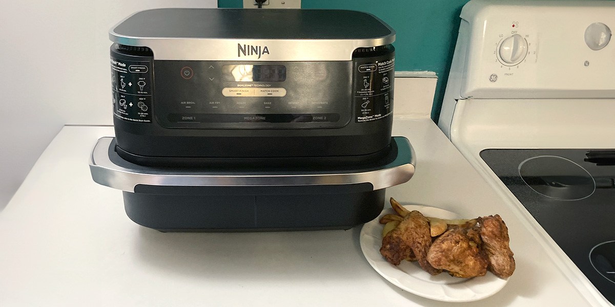 Large-capacity air fryer next to plate of chicken wings and fries
