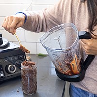 Person using wooden spoon with blender