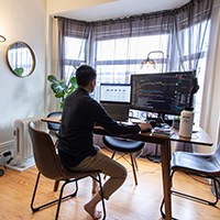 a person sitting in front of a laptop and a monitor
