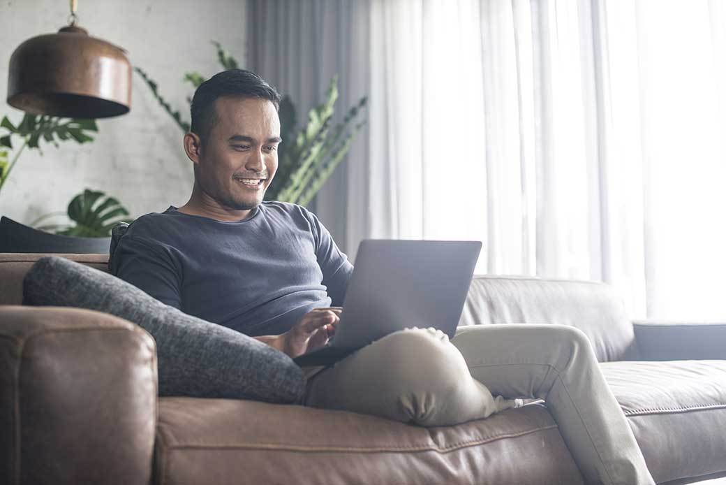 Person sitting on couch working on laptop