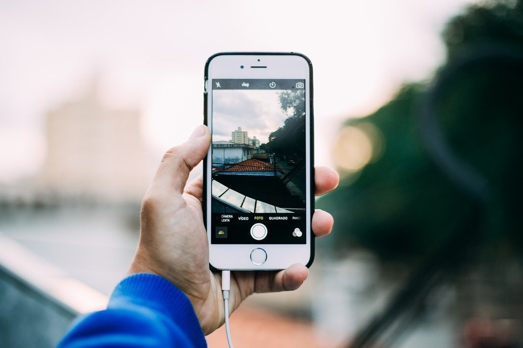 A hand holds an iPhone in front of an indistinct, but lovely, background