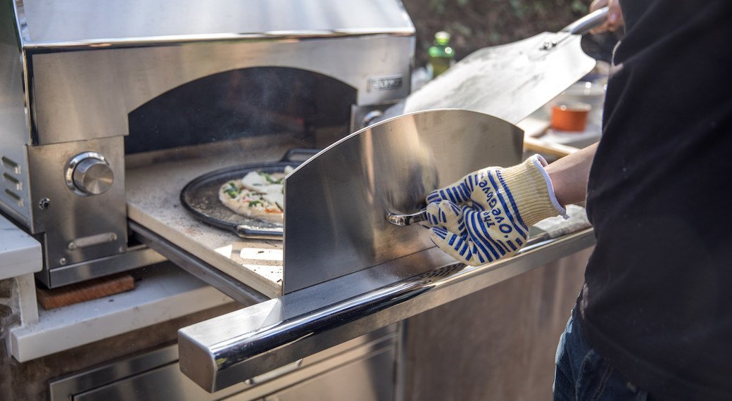 Pizza on a pizza pan sliding into a pizza oven