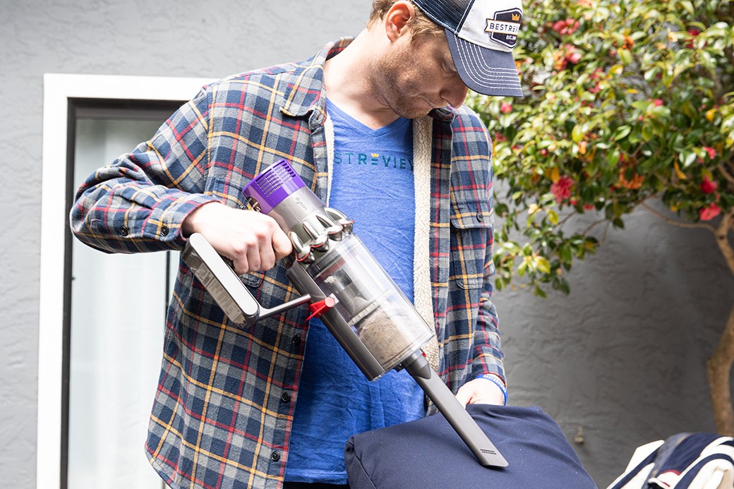 Person vacuuming patio cushion with handheld vacuum