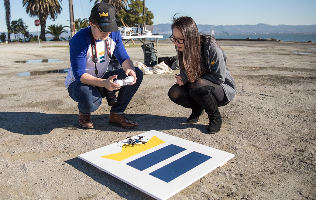 Two people looking at drone on landing pad