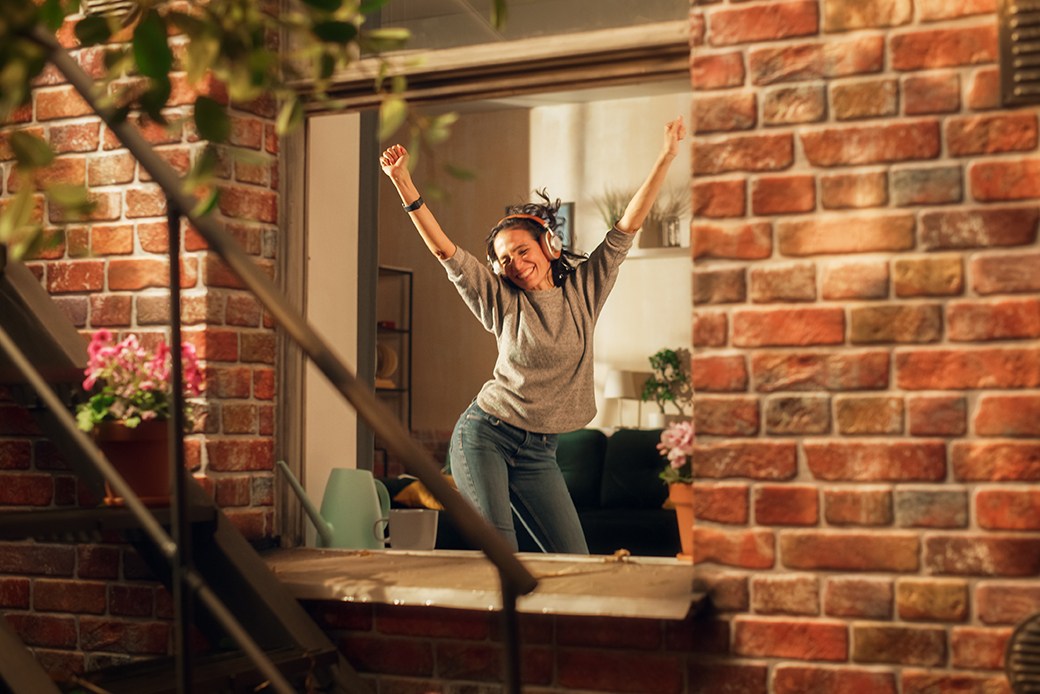Woman wearing headphones dancing in apartment
