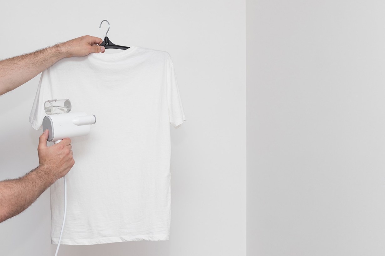 using a handheld steamer on a white t-shirt