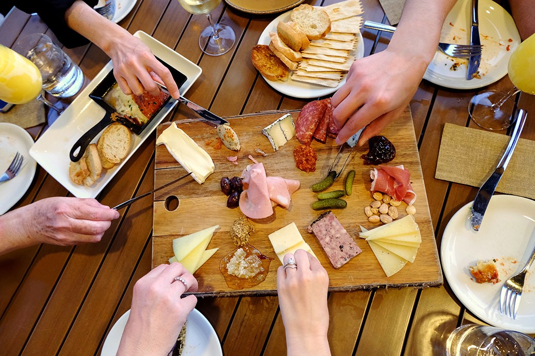People eating from charcuterie board