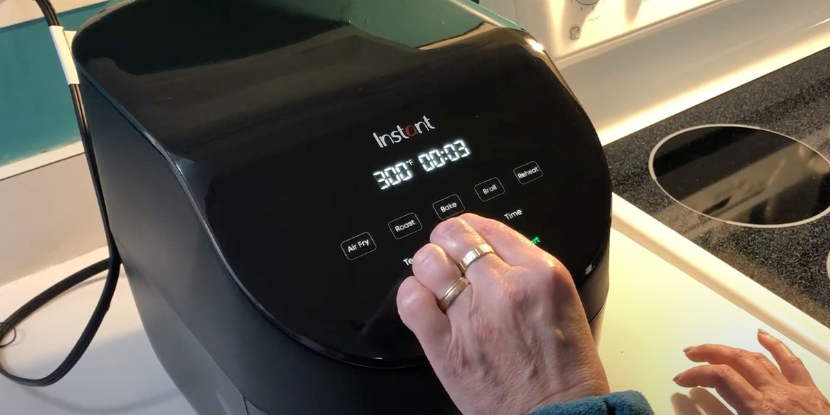 Hand using Instant Vortex Slim 6-quart Air Fryer's controls