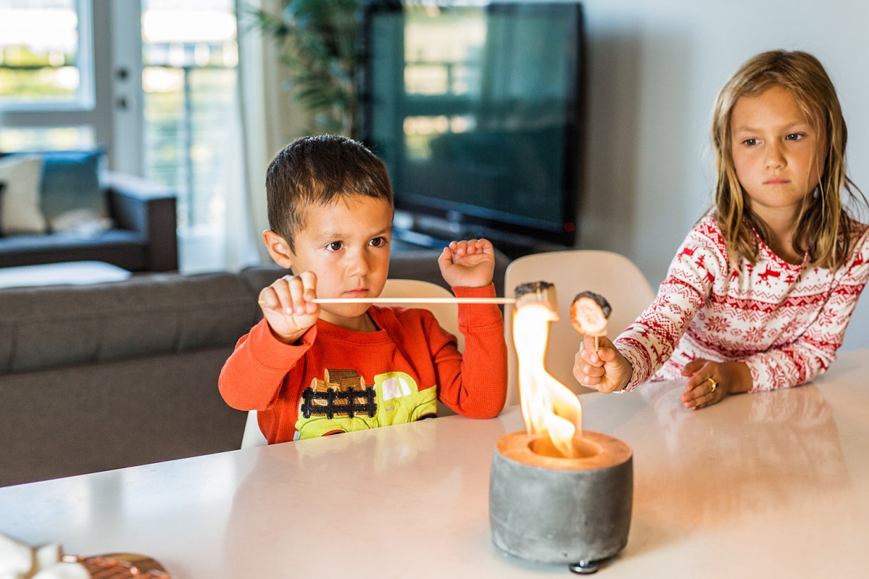 two children roasting marshmallows using a tabletop fire pit