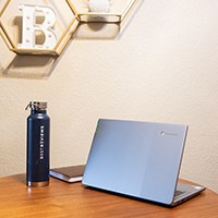 a laptop on a table next to a water bottle